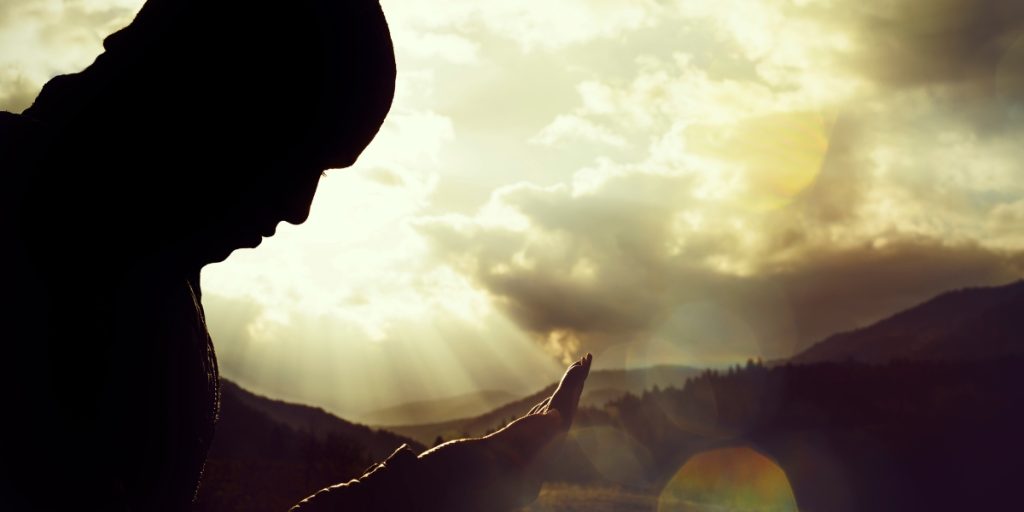 Man wolding his hands out under yellow clouds